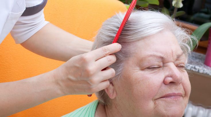 Pflegerin kämmt Seniorin durch die Haare